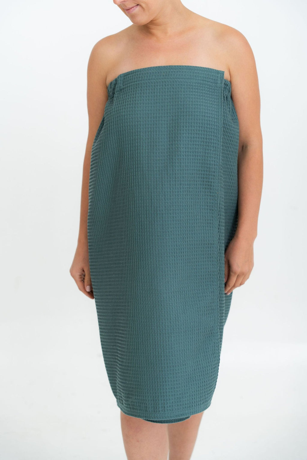 2. Woman wearing petrol cotton waffle sauna wrap in studio setting
