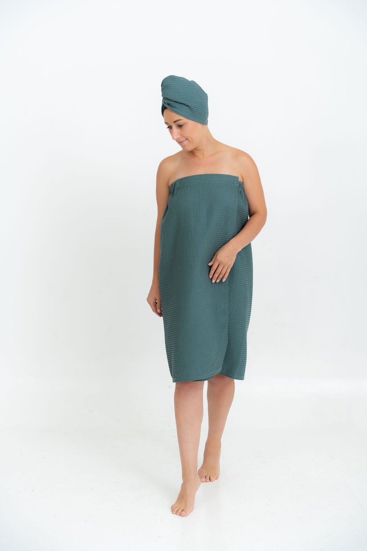 1. Woman in petrol cotton waffle sauna wrap with matching head wrap, walking in studio setting