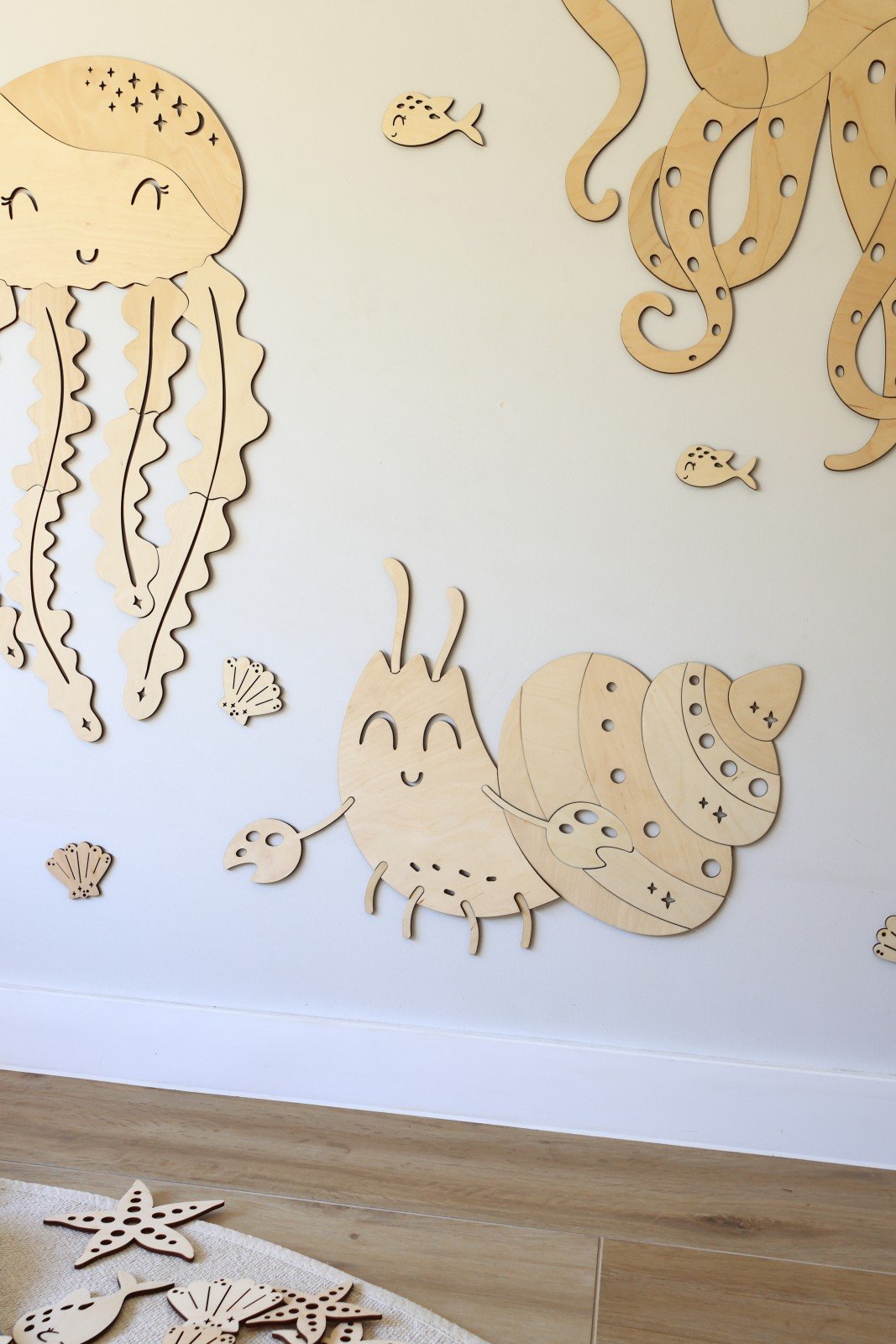 1. Children's room with wooden ocean-themed wall decorations including a crab, jellyfish, and octopus on a white wall