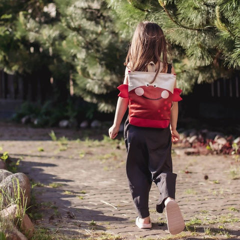 2. Girl walking with Muni kids crab backpack, highlighting back view and outdoor setting
