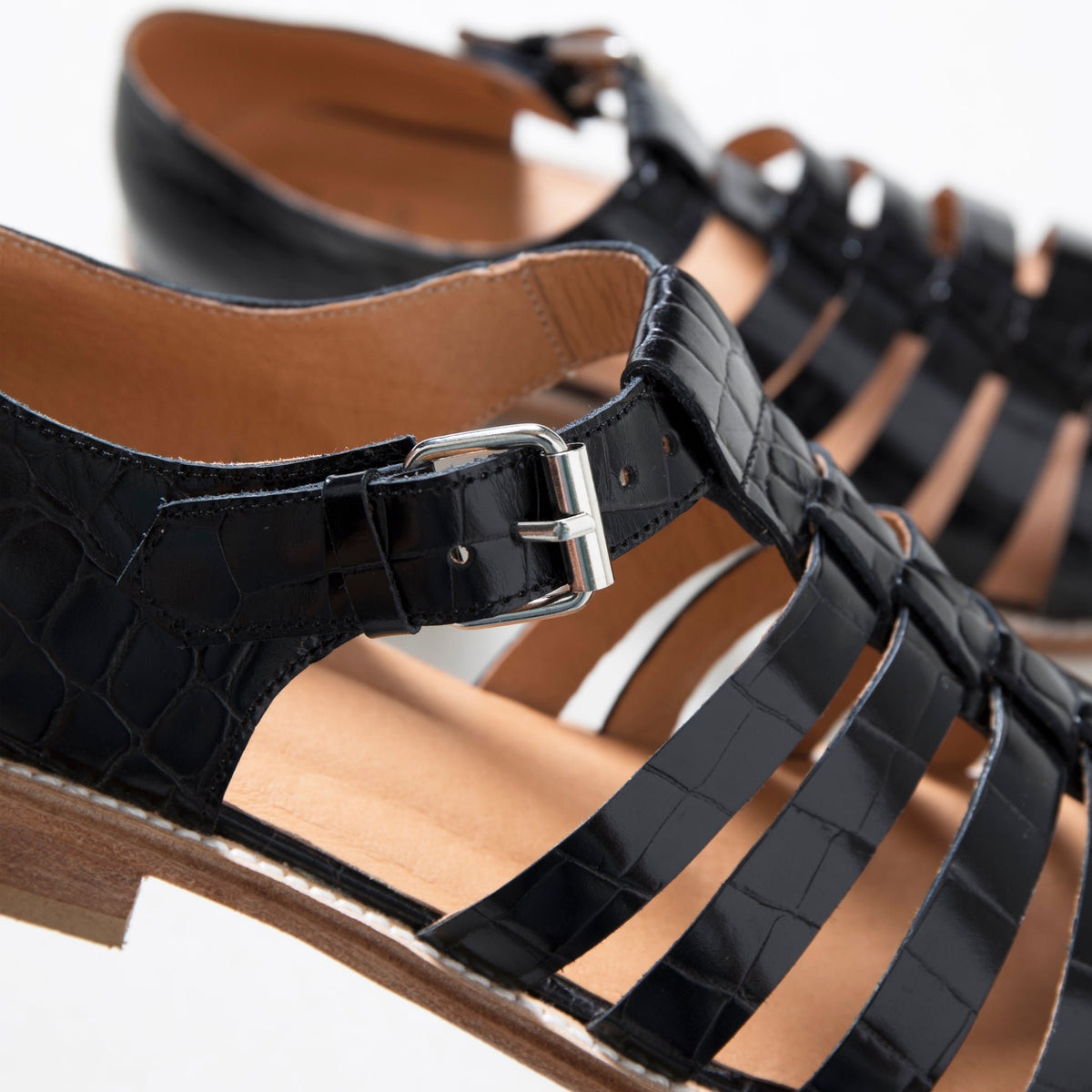 5. Close-up of silver-tone buckle and strap detail on black croc fisherman sandals