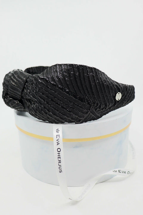 4. Close-up of Eva Oherjus Knot Headband Holly in black with metallic threads, displayed on a luxury hat box