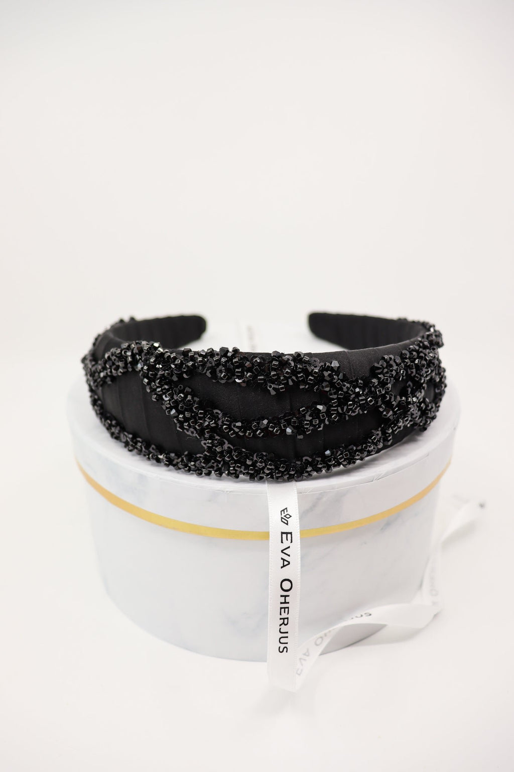 6. Eva Oherjus Mulberry Silk Beaded Headband Hestia displayed on a luxury hat box, showcasing brand tag and intricate beadwork