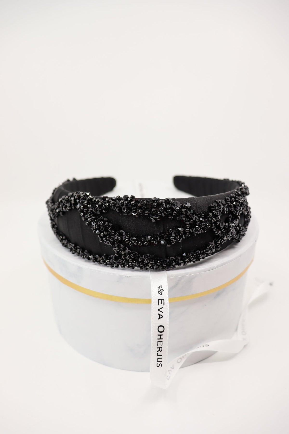 6. Eva Oherjus Mulberry Silk Beaded Headband Hestia displayed on a luxury hat box, showcasing brand tag and intricate beadwork