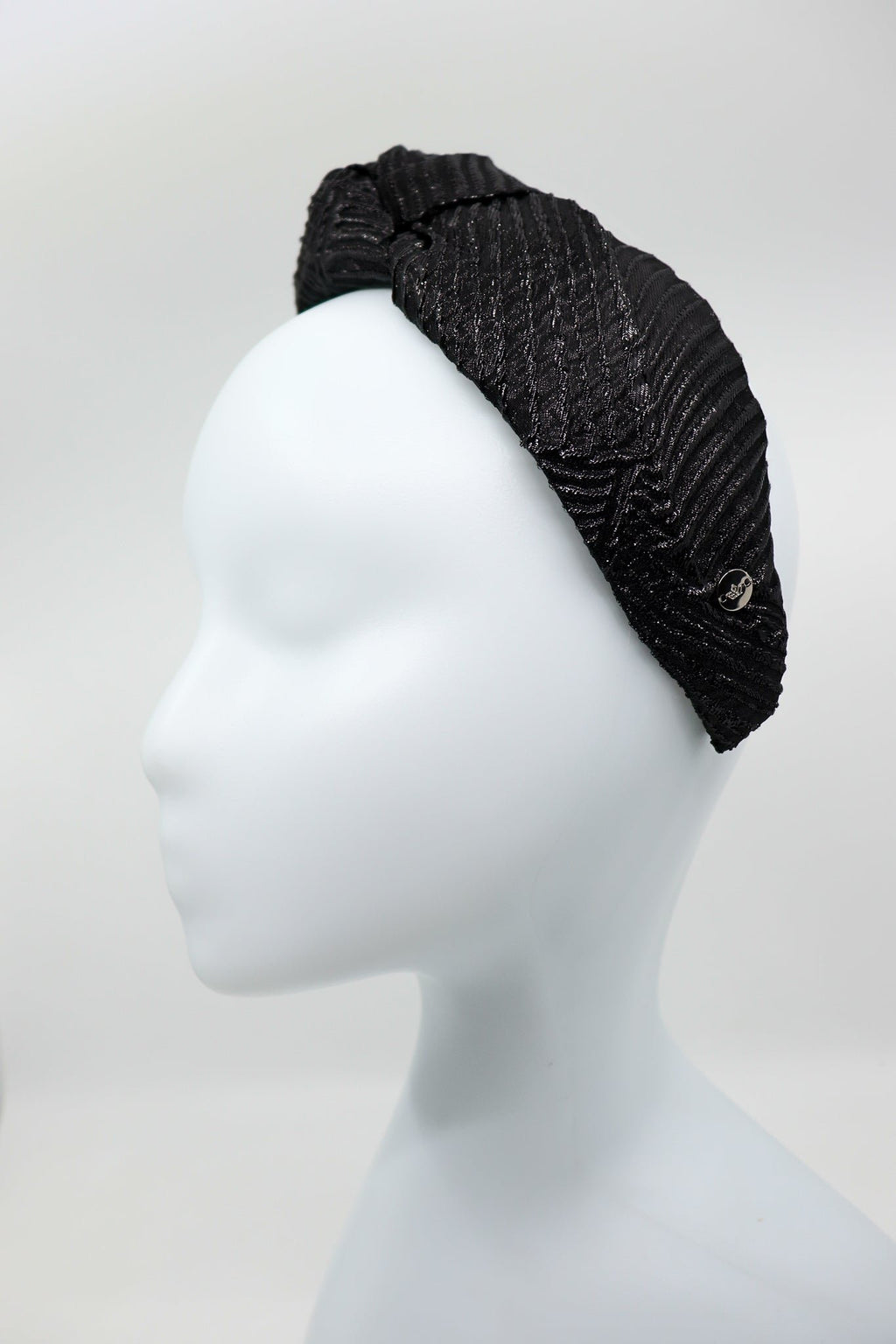 2. Studio shot of Eva Oherjus Knot Headband Holly in black with metallic threads on a mannequin, side view