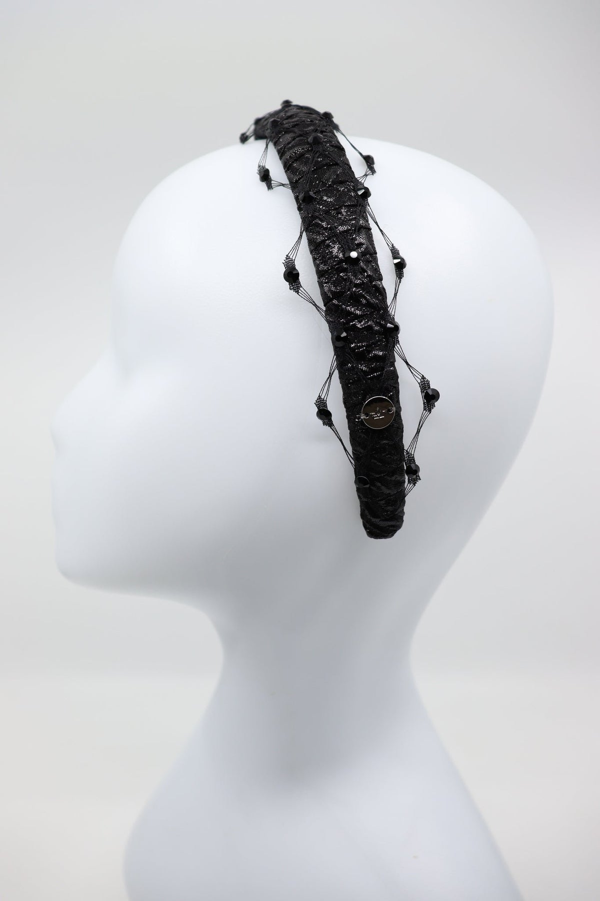 2. Studio shot of Slim Headband Naomi featuring black fabric and honeycomb veil with Swarovski crystals