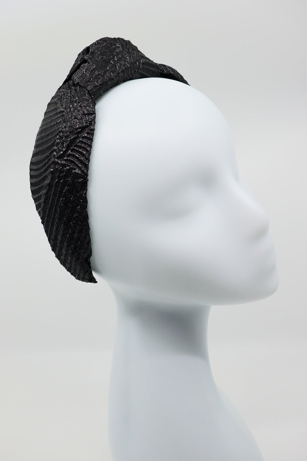 3. Studio image of Eva Oherjus Knot Headband Holly in black with metallic threads on a mannequin, front view