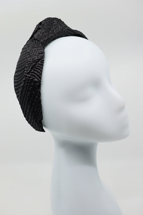 3. Studio image of Eva Oherjus Knot Headband Holly in black with metallic threads on a mannequin, front view