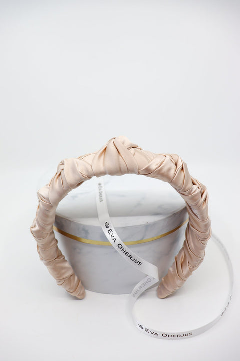 4. Front view of Eva Oherjus Jenna Mulberry Silk Knotted Headband in light beige, highlighting knotted design on hat box