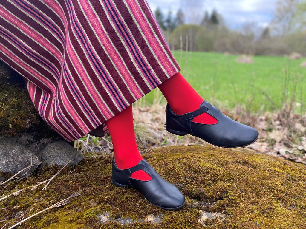 2. Women's black Kergatsi dance shoes by OmaKing styled with red tights and striped skirt, shown in nature