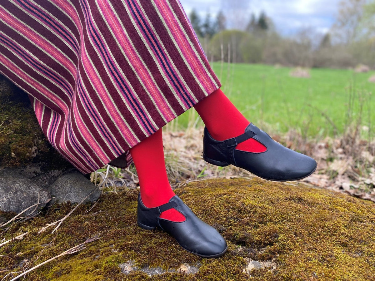 2. Women's black Kergatsi dance shoes by OmaKing styled with red tights and striped skirt, shown in nature