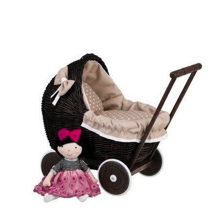 5. Dark painted wicker doll pram with beige bedding and a doll in pink dress beside it, studio setting