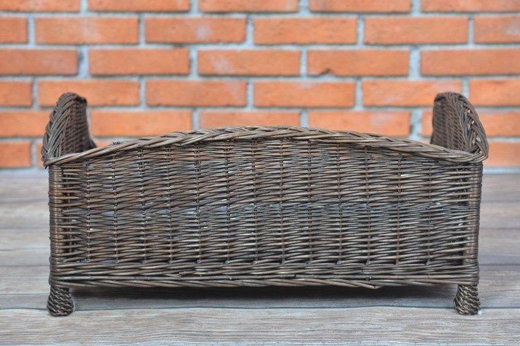 4. Back view of dark wicker pet bed against brick wall, showing woven design