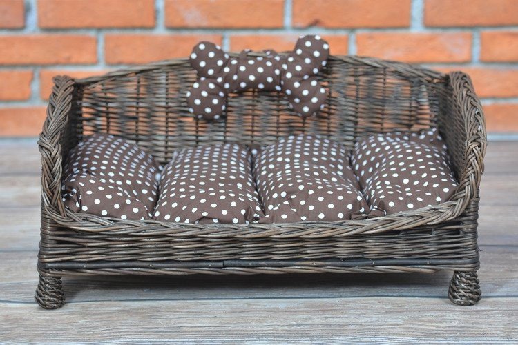 1. Dark wicker pet bed with brown polka dot cushion and decorative bone against brick wall