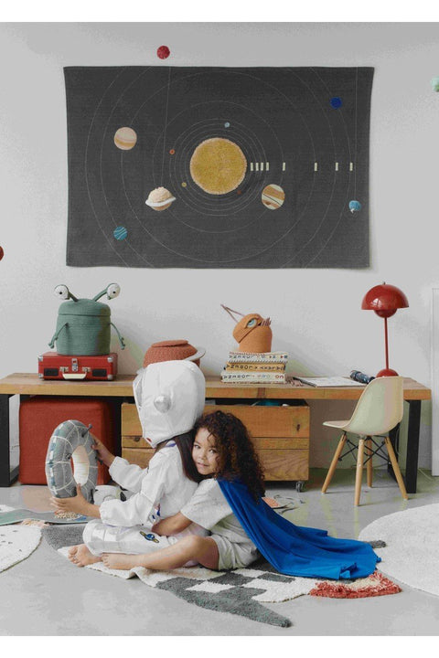 1. Two children playing in a space-themed room with a green alien basket on a desk, featuring a solar system wall hanging