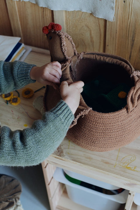2. Close-up of Lorena Canals chicken pouf being opened by a child, showing its functional storage space