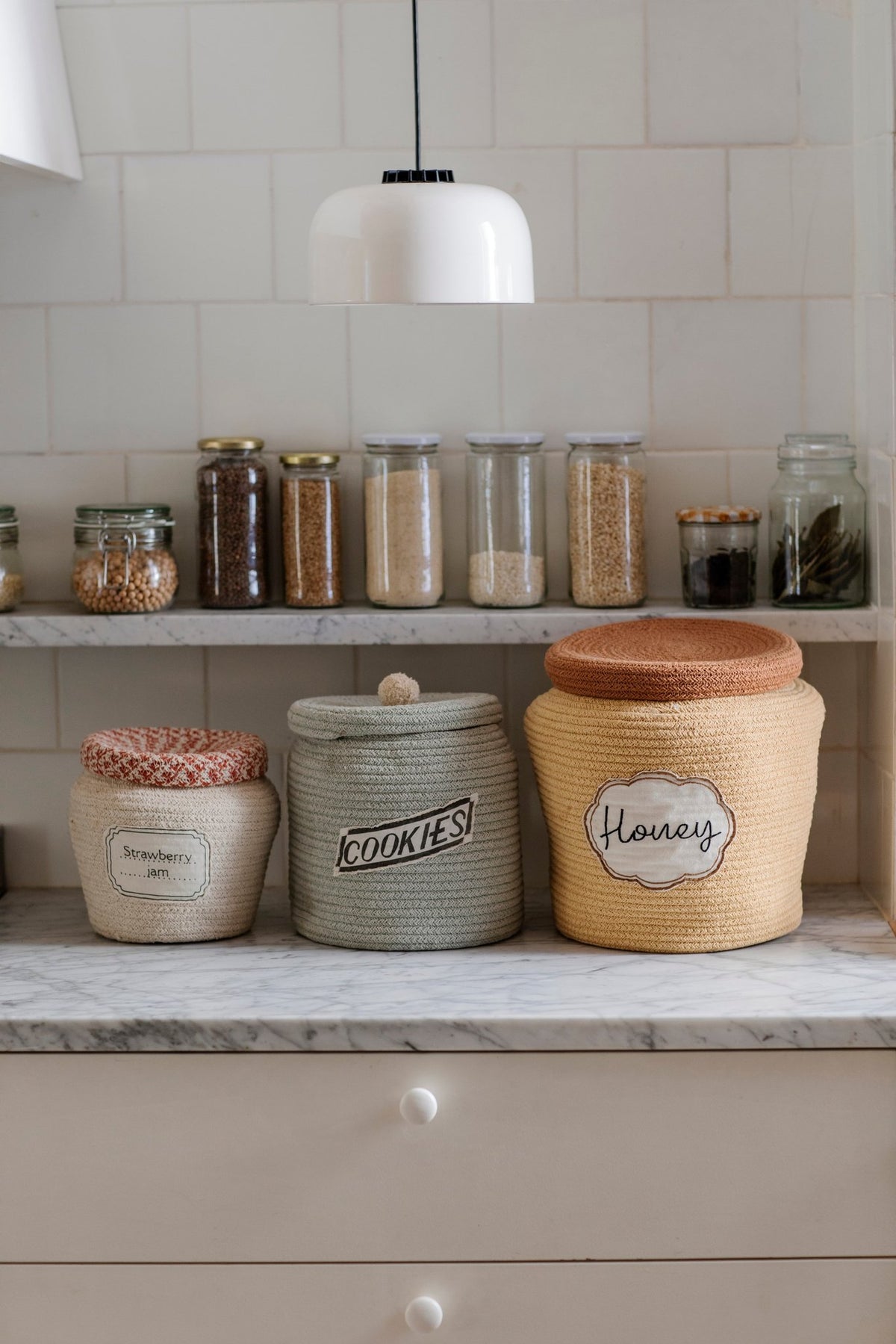 1. Kitchen shelf with three decorative baskets, including a honey yellow basket with toffee brown lid labeled 'Honey', surrounded by jars and spices
