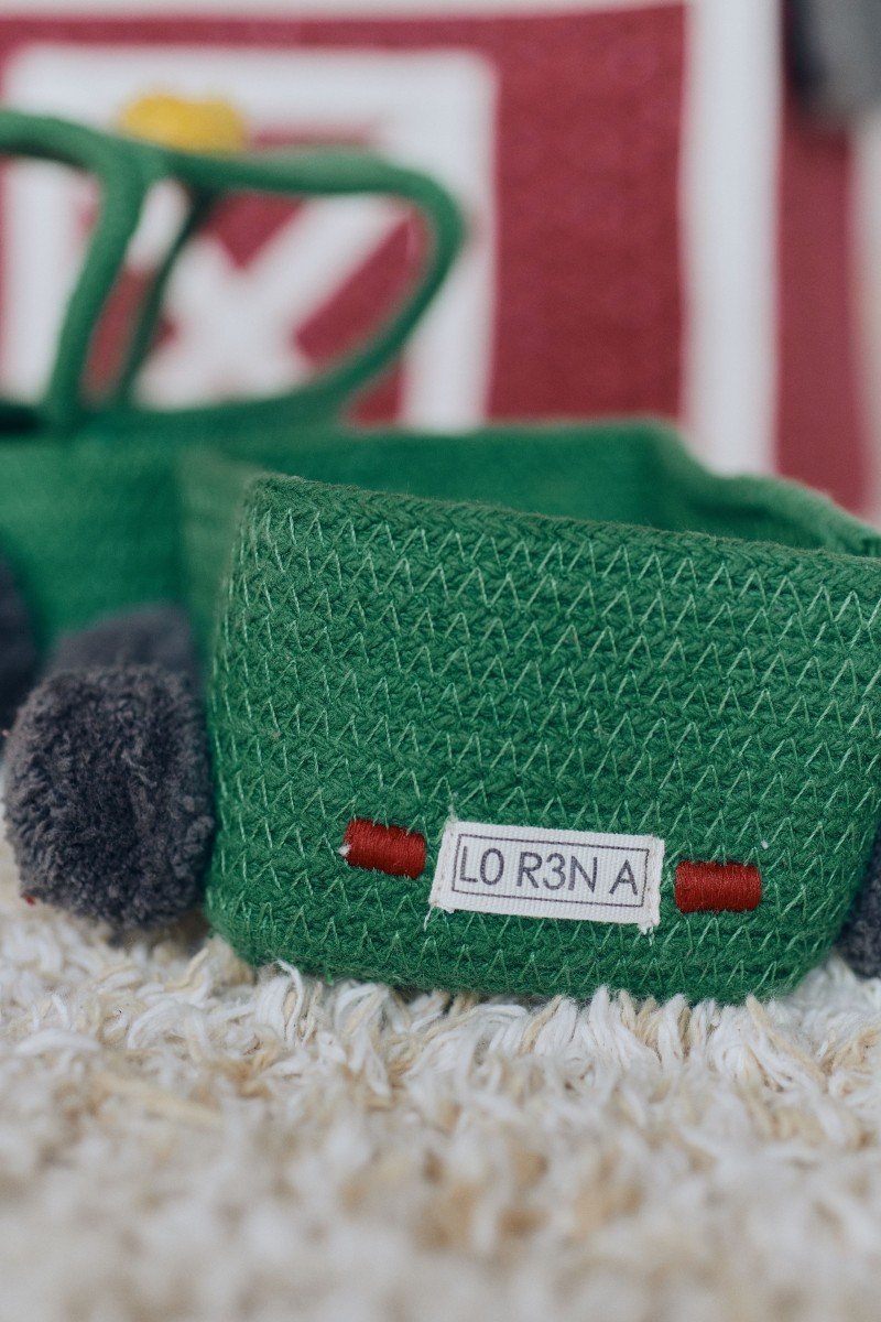 3. Close-up of green tractor basket showing license plate with 'L0 R3 NA' text and black pompom wheels
