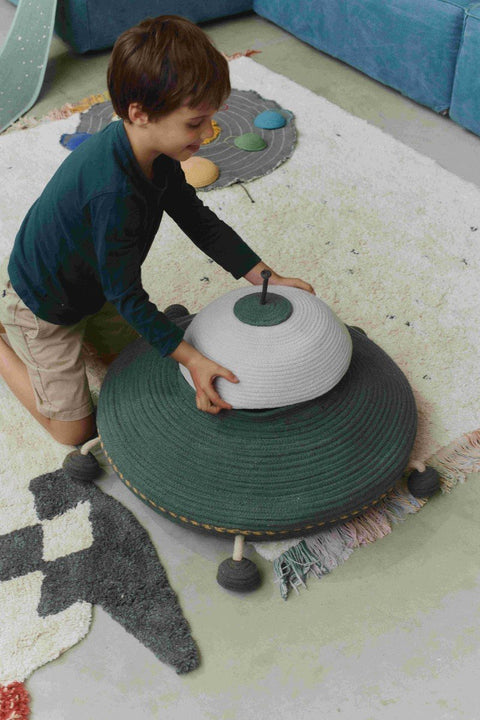 1. Child playing with Lorena Canals UFO basket, lifting the lid to reveal interior, in a colorful playroom