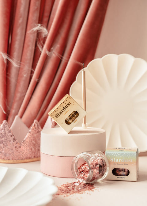 2. Decorative eco glitter gold star dust in a glass jar with packaging, set against a pink and white backdrop with decorative elements