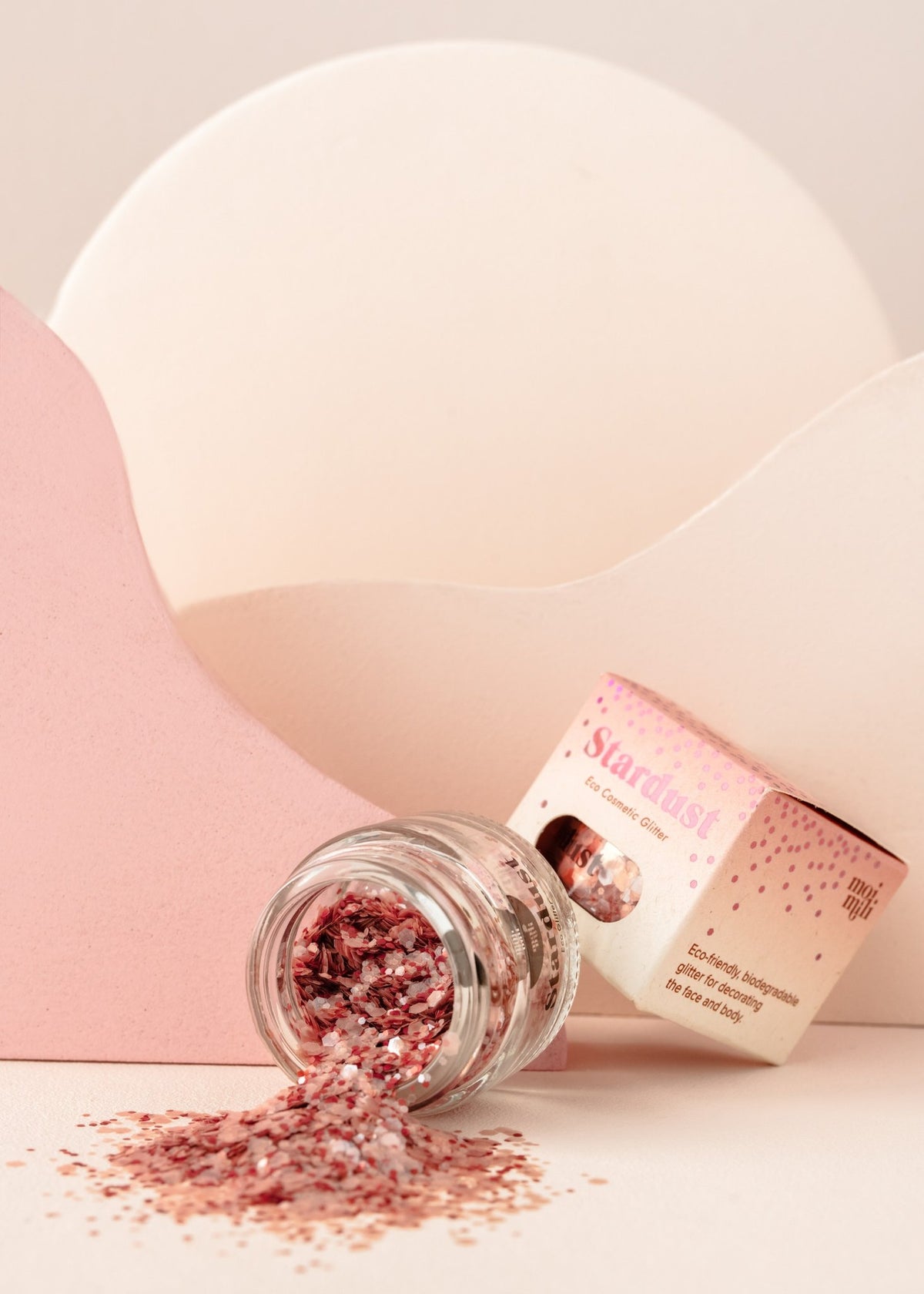 2. Glass jar of pink eco glitter spilled on pink and white background with packaging