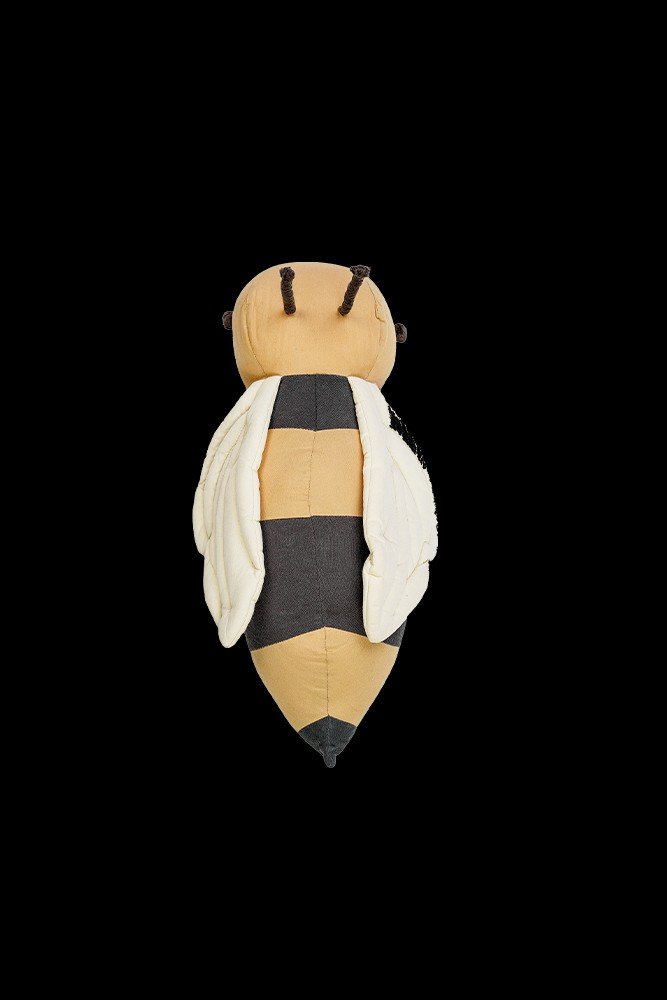 2. Bee-shaped pillow with honey and dark gray stripes shown from top on black background