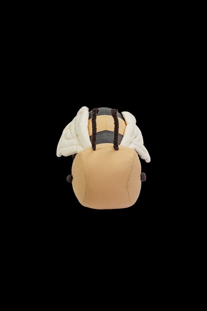2. Front view of bee-shaped pillow with honey-colored face and natural wings on black background