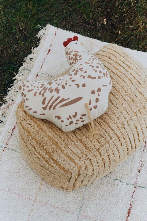 3. Beige chicken-shaped pillow with brown details on a textured beige cushion outdoors