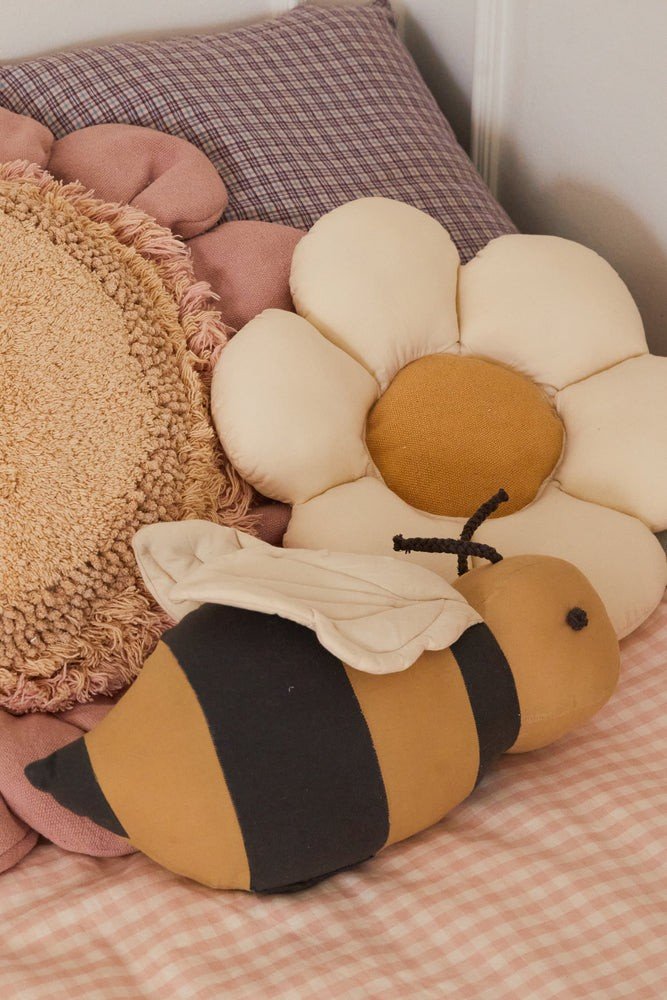 3. Decorative daisy pillow with natural-colored petals and honey center on a bed with a plush bee toy