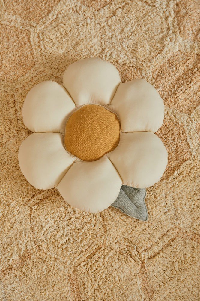 1. Decorative pillow shaped like a daisy with natural-colored petals and a honey-colored center on a textured beige rug