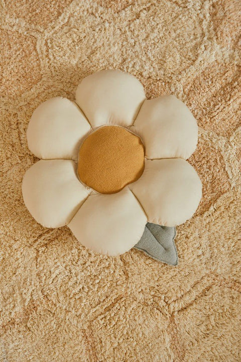 1. Decorative pillow shaped like a daisy with natural-colored petals and a honey-colored center on a textured beige rug