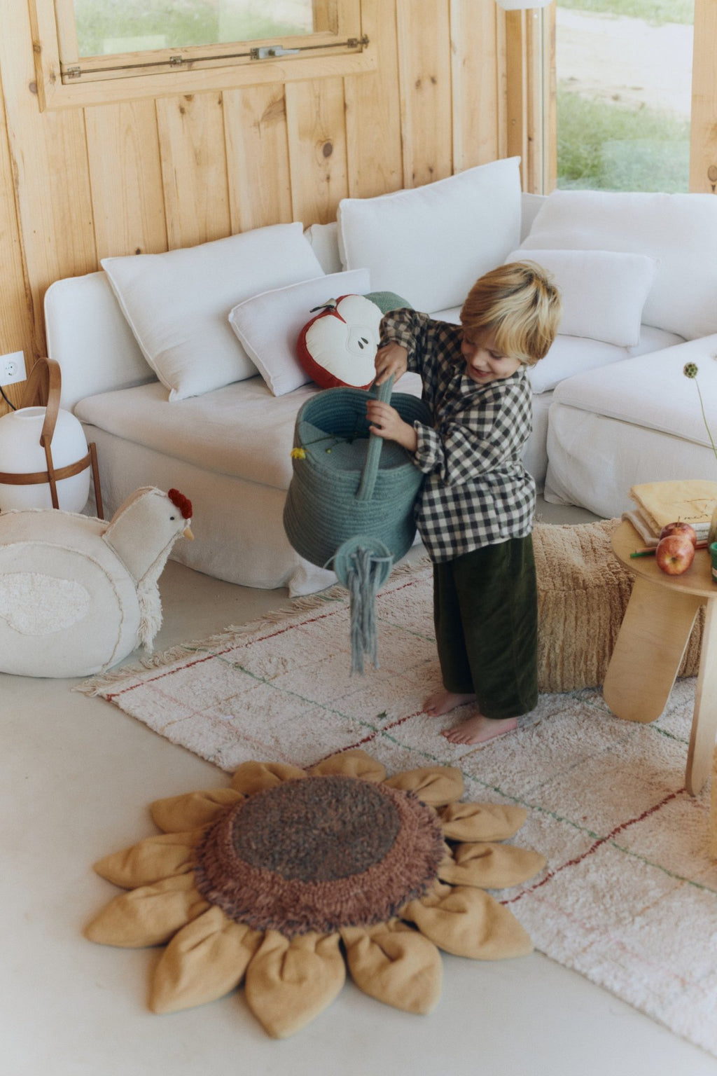 1. Child playing with blue decorative basket watering can in cozy living room