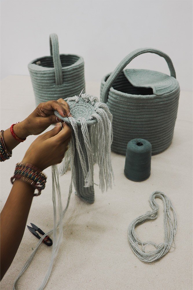 3. Close-up of hands weaving cotton strings on blue decorative basket watering can