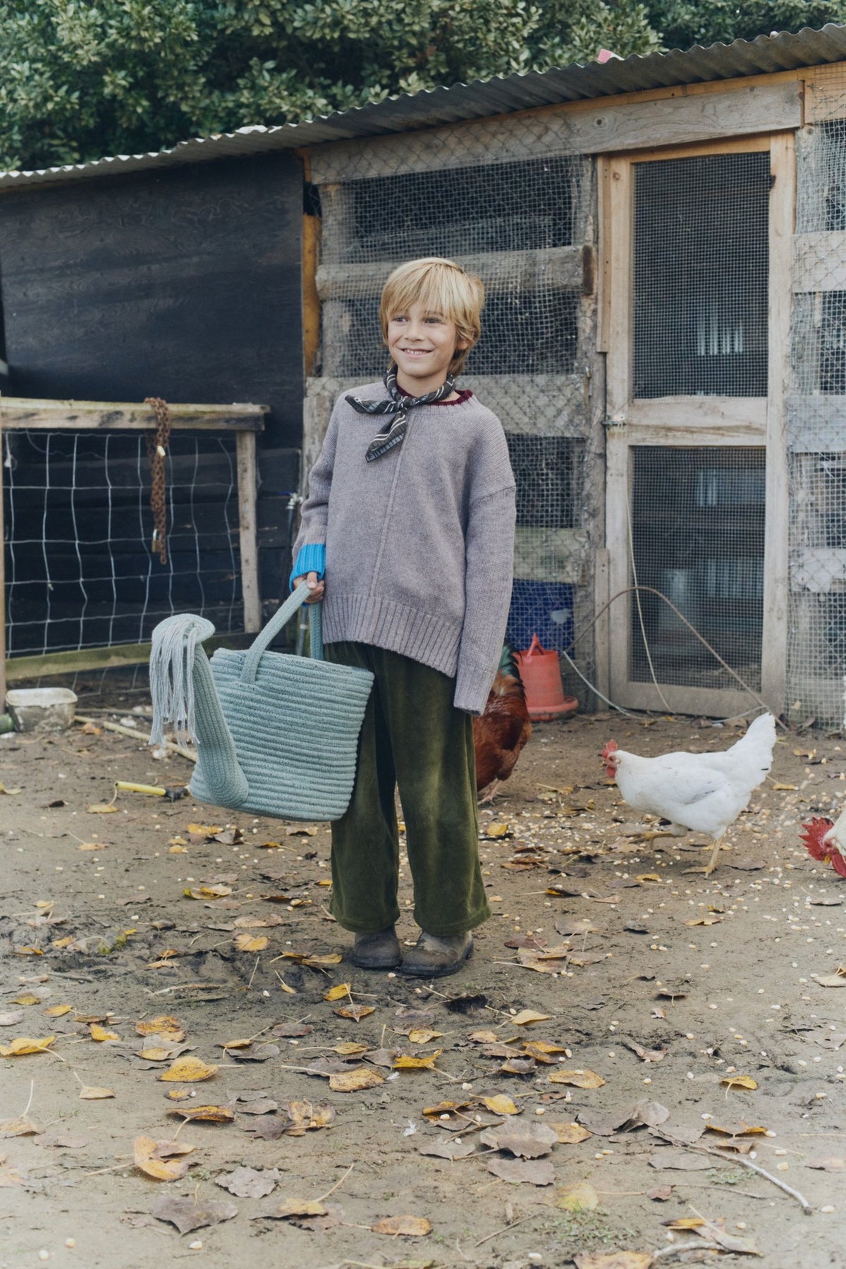 1. Child holding blue decorative basket watering can in rustic outdoor setting with chickens