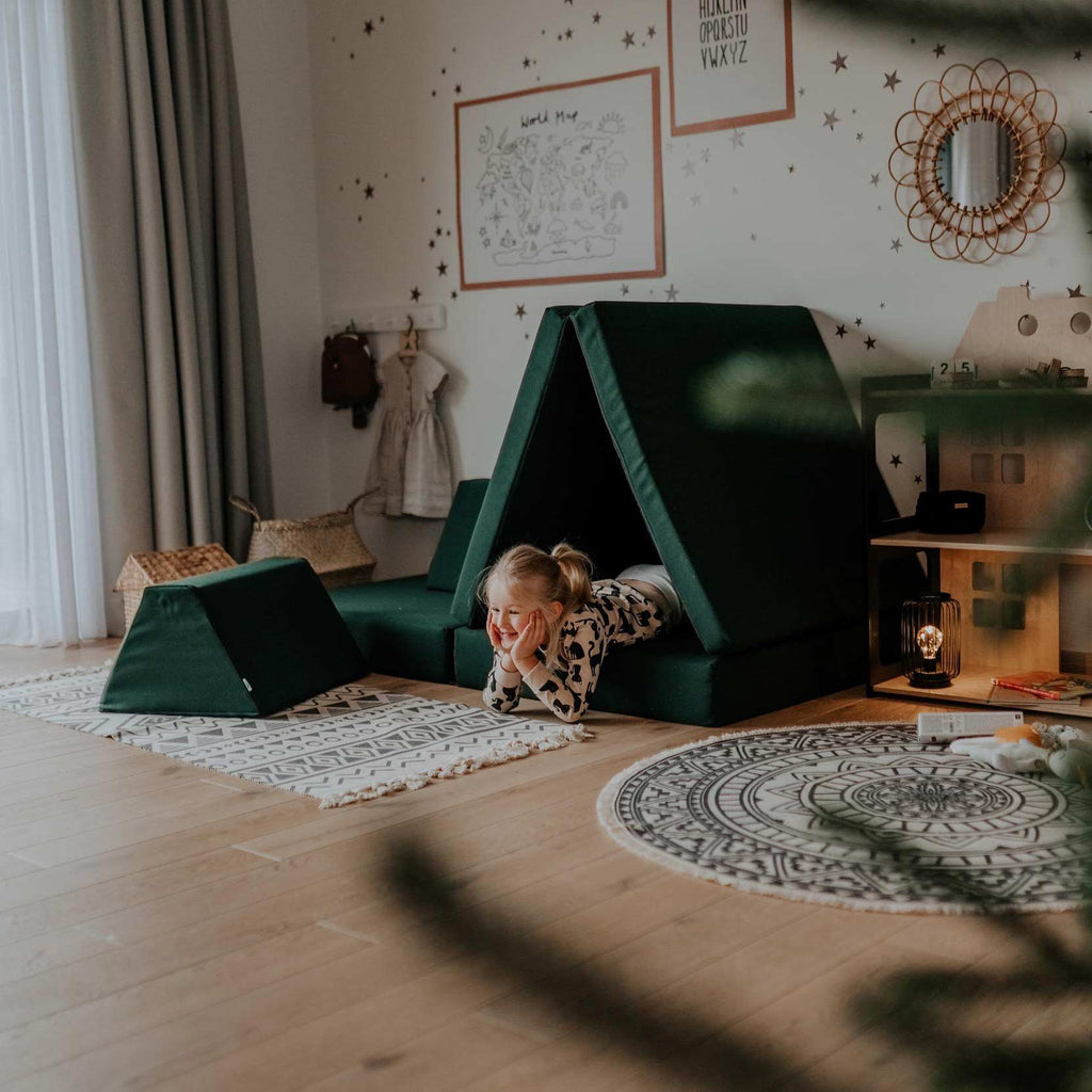 1. Child playing inside Monboxy deep green play mattress set arranged as a tent in a decorated room