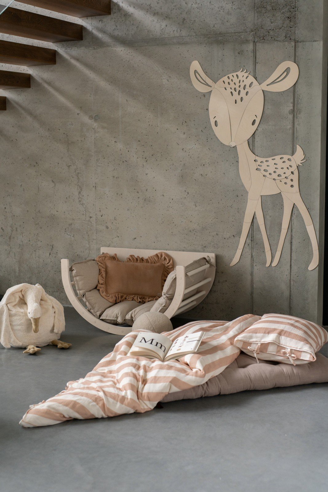 7. Deer wooden wall decoration in nursery with beige and pink bedding and plush toys