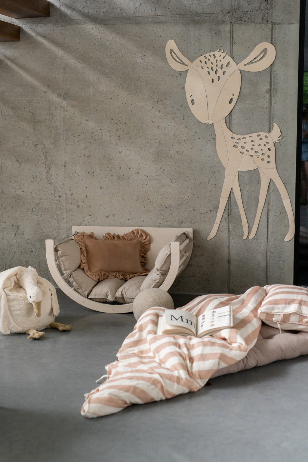 9. Deer wooden wall decoration in nursery with cozy seating and open book on bed