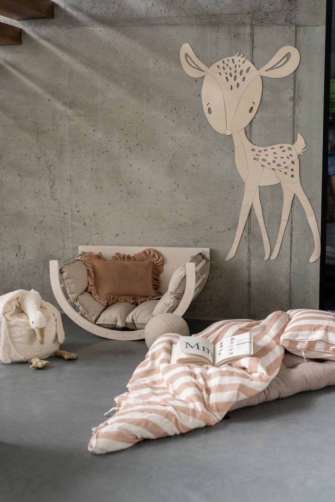 9. Deer wooden wall decoration in nursery with cozy seating and open book on bed