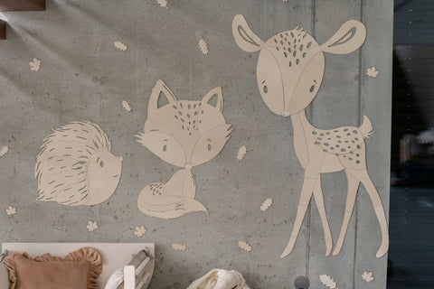 5. Deer, fox, and hedgehog wooden wall decorations on concrete wall with scattered leaves