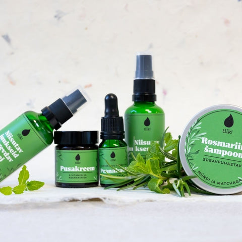 2. Collection of Tilk! hair care products including Detangling Cream, Rosemary Shampoo, and oils, displayed with fresh herbs