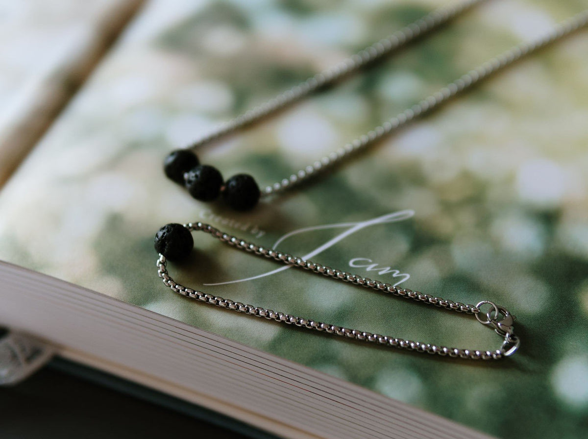 3. Canary Lava black lava stone necklace and bracelet set displayed on a book, highlighting golden chain and natural volcanic rock beads
