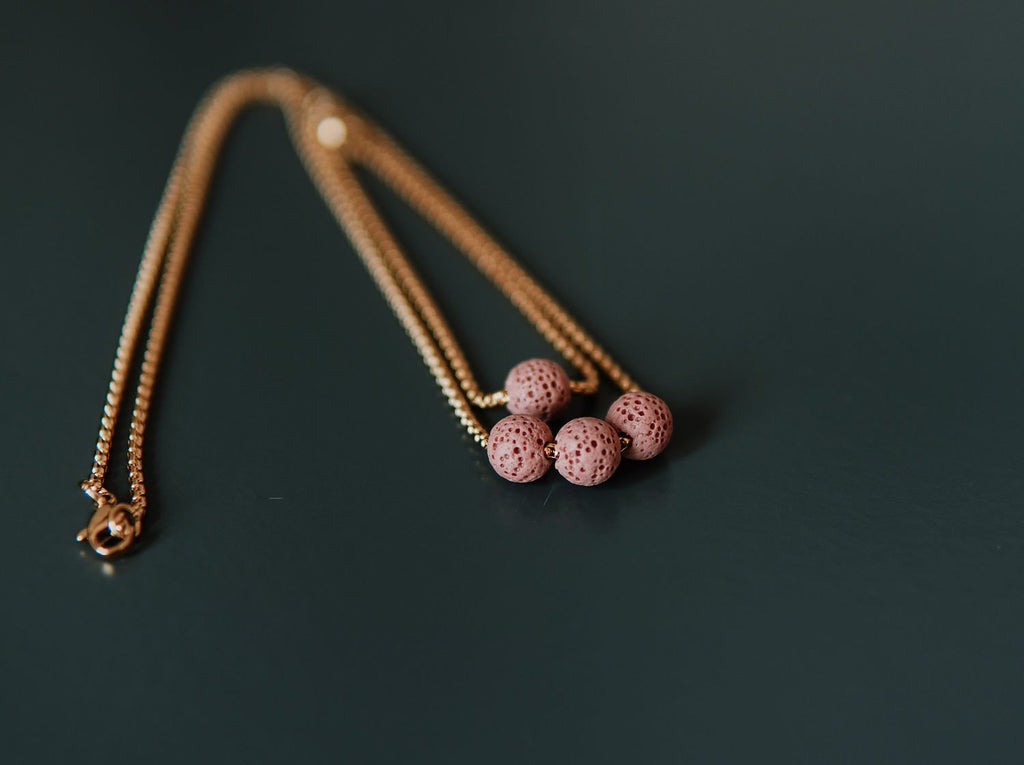 1. Pink lava stone necklace with three beads on a golden stainless steel chain, shown in a studio setting
