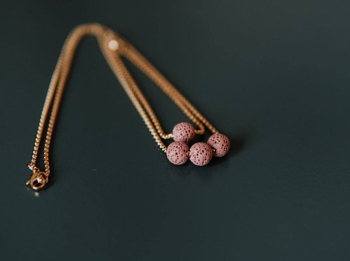 1. Pink lava stone necklace with three beads on a golden stainless steel chain, shown in a studio setting