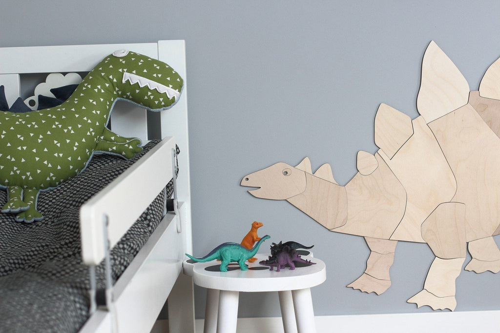 2. Wooden stegosaurus wall decoration in child's room with dinosaur toys on white table