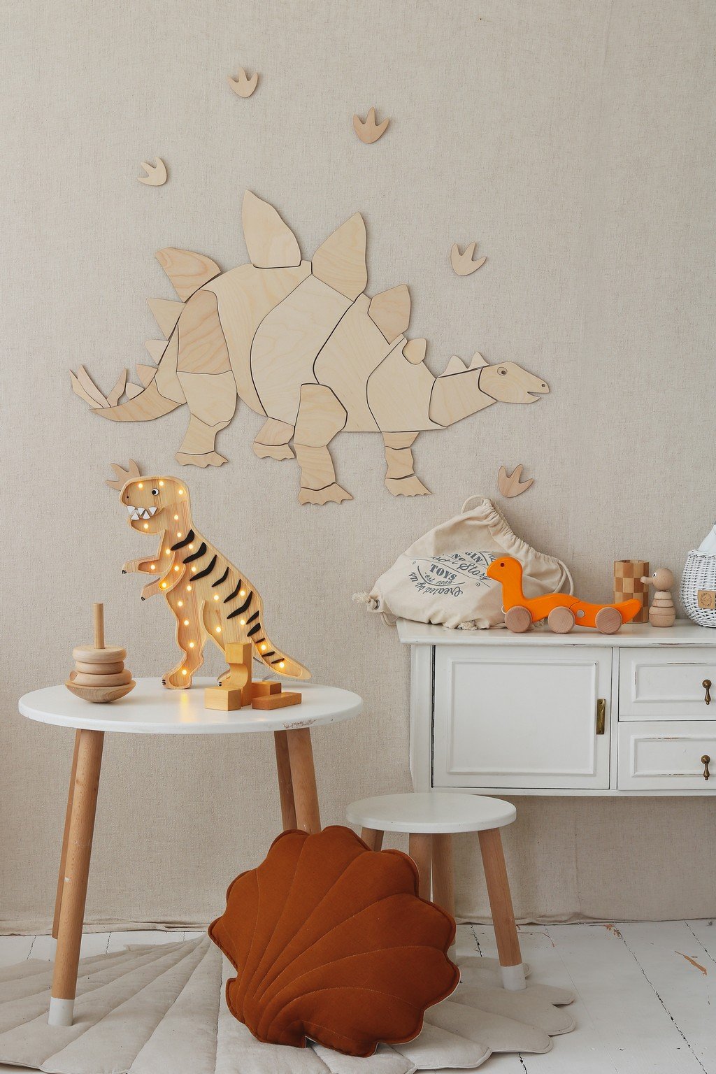 3. Wooden stegosaurus wall decoration with puzzle design above white cabinet and toys