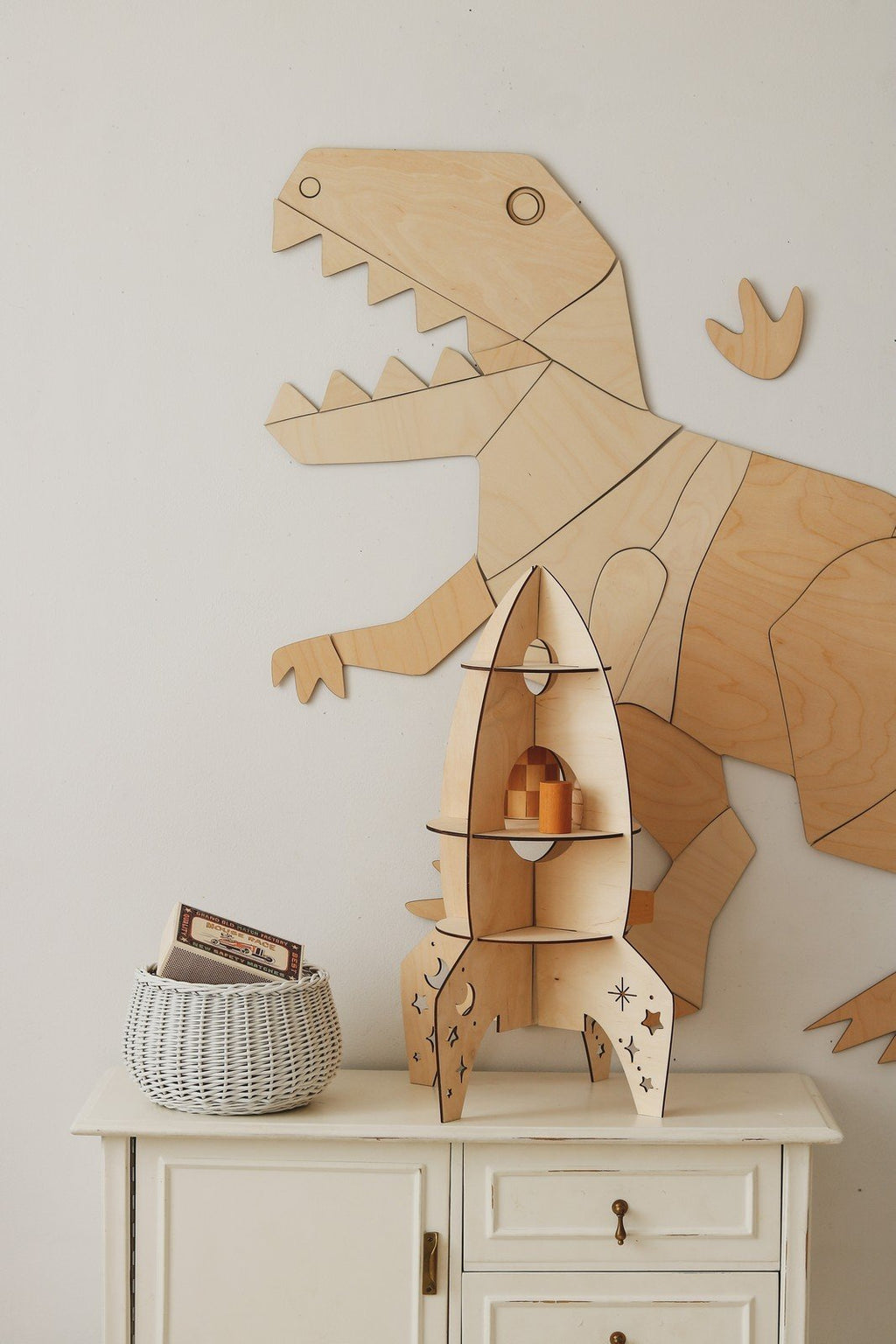 5. Wooden T-Rex wall decoration with rocket shelf and basket, complementing a child's room decor
