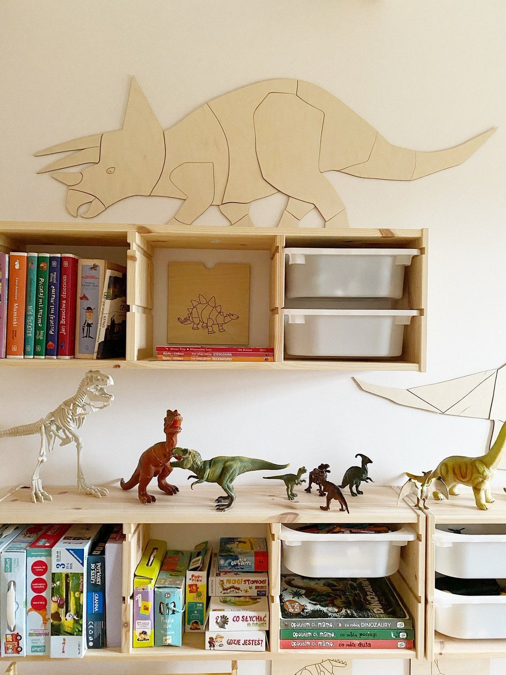 6. Wooden Triceratops wall decoration mounted above wooden shelves with books and dinosaur toys