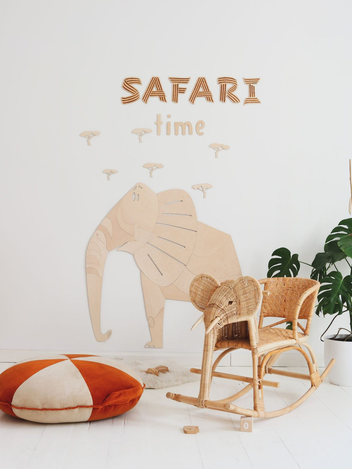 2. Safari-themed room with wooden elephant wall decoration, wicker rocking chair, and orange cushion