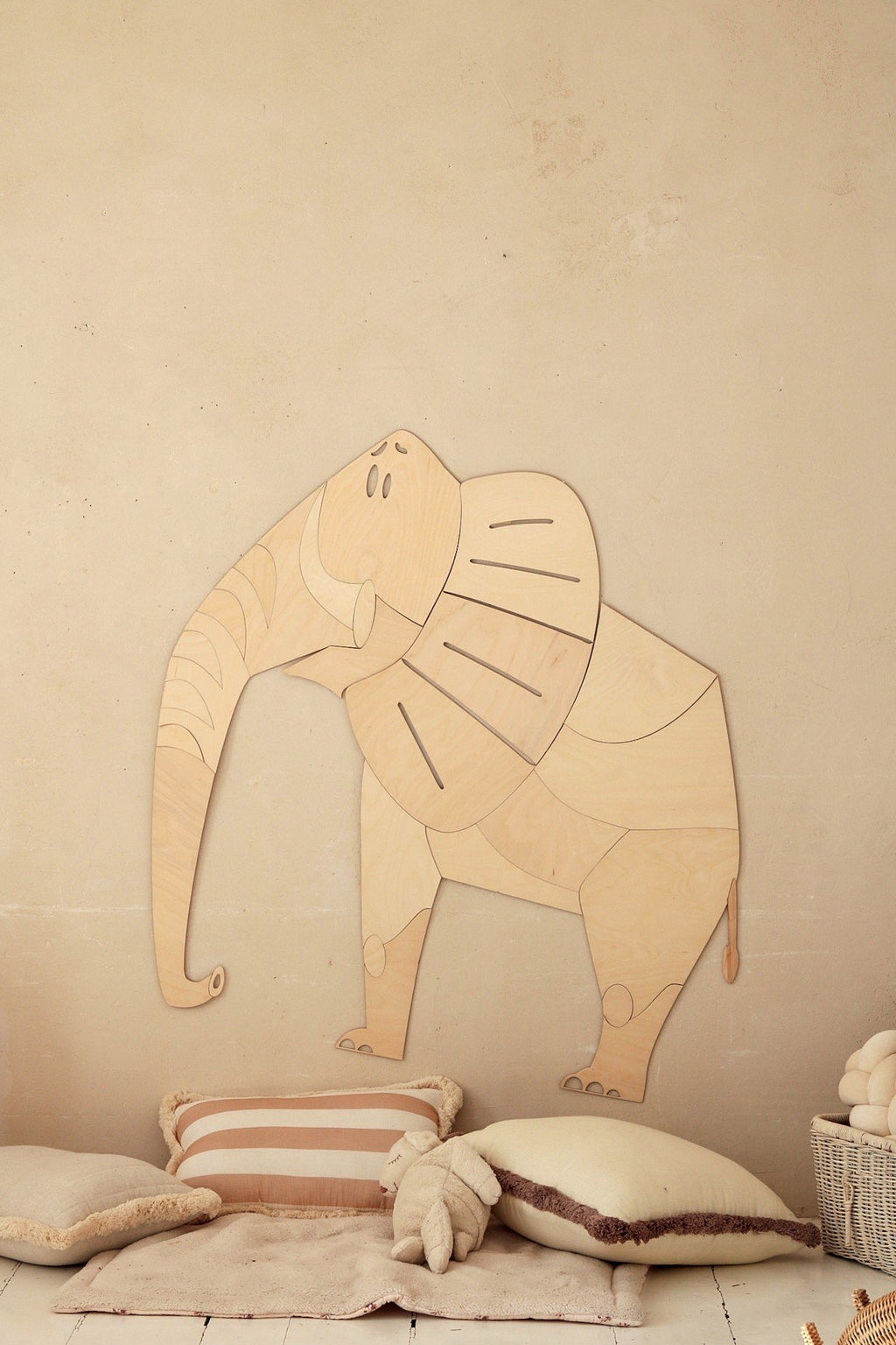 3. Wooden elephant wall decoration above cushions in child's room, natural tones