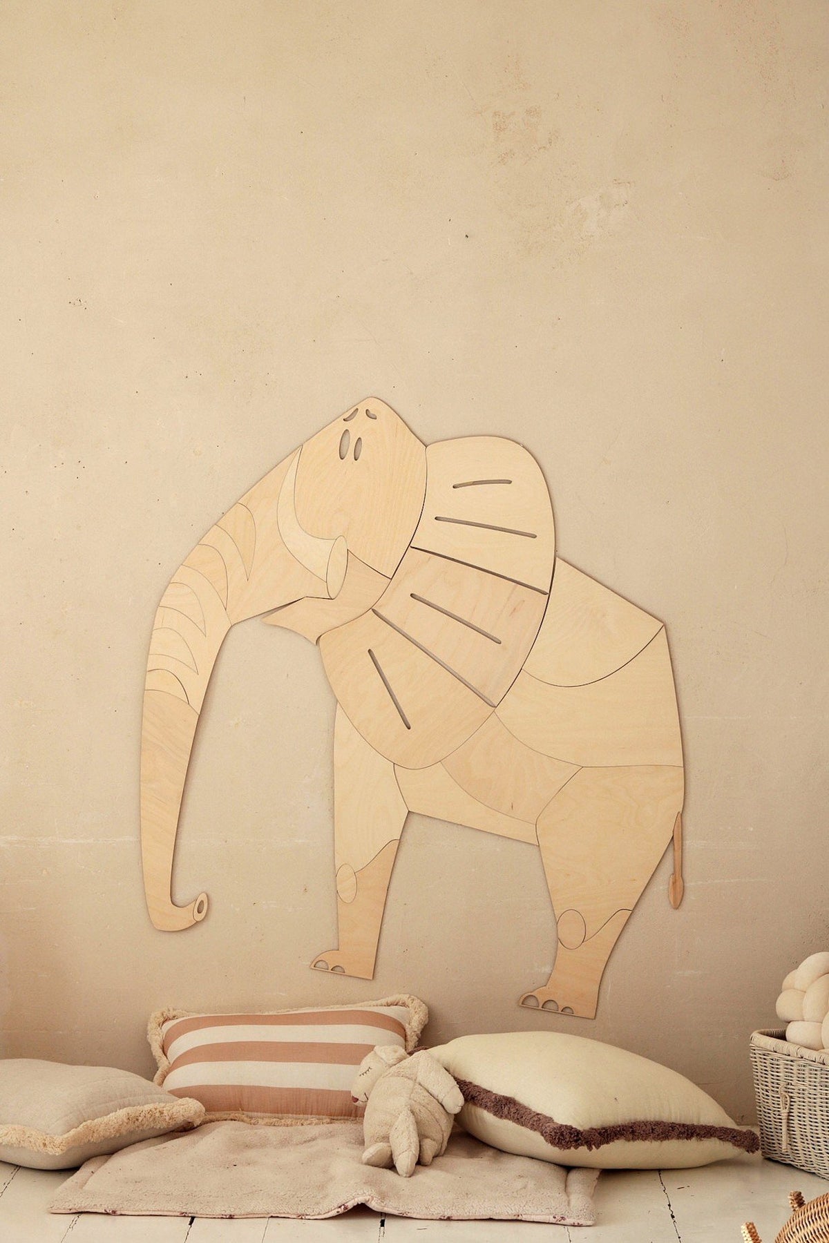 3. Wooden elephant wall decoration above cushions in child's room, natural tones